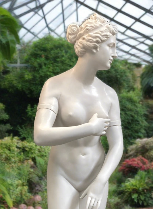 Statue of a nude woman in a greenhouse setting