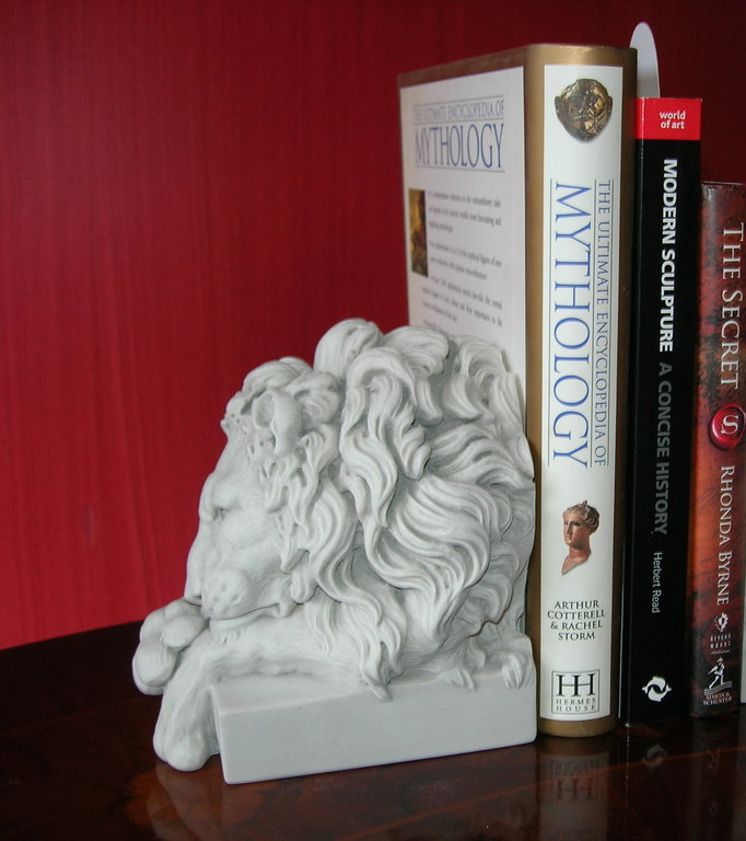 White lion head sculpture with books on a red background