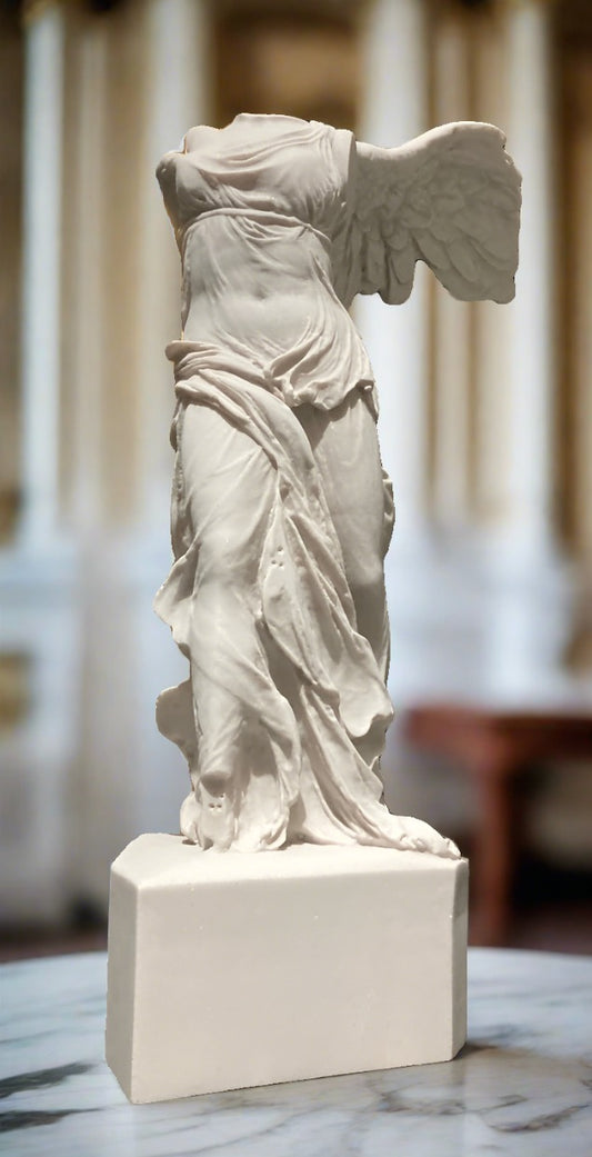 A white marble statue of the goddess Nike, dated back to 190 BC, with outstretched wings and a dynamic pose, displayed on a pedestal.