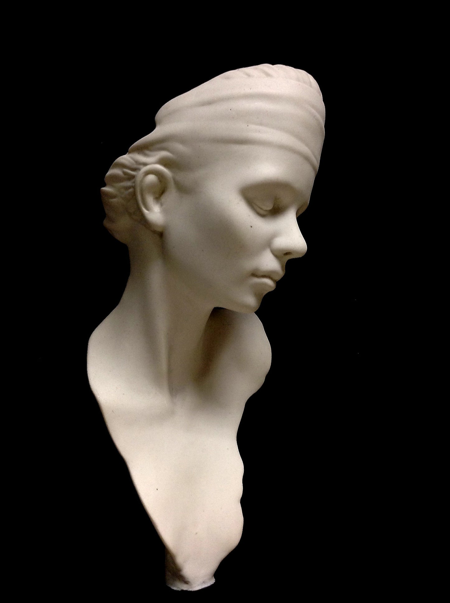 A white marble sculpture of a young lady with her head slightly lowered and eyes closed, set on a plain pedestal.