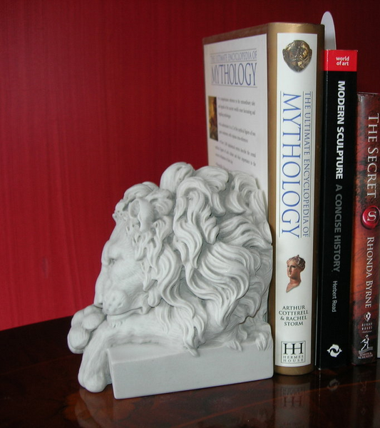 White lion head sculpture with books on a red background